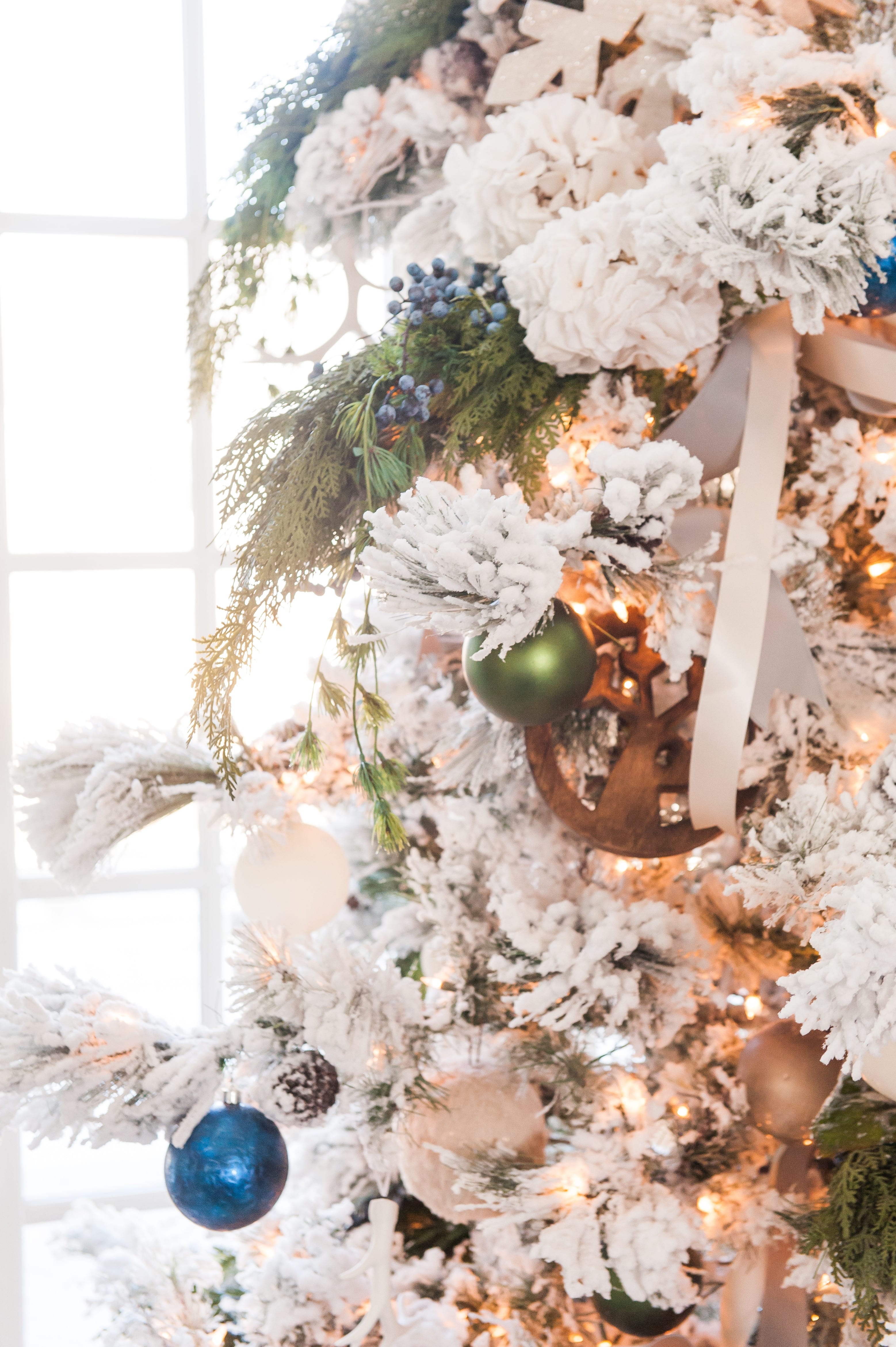 Christmas tree flocked long needle pine christmas tree flocked tree blue decor blue christmas ornaments trimming the tree shades of blue on white blue and cream flocked long needle pine artificial tree blue white ivory cream silver ornaments plaid ribbon