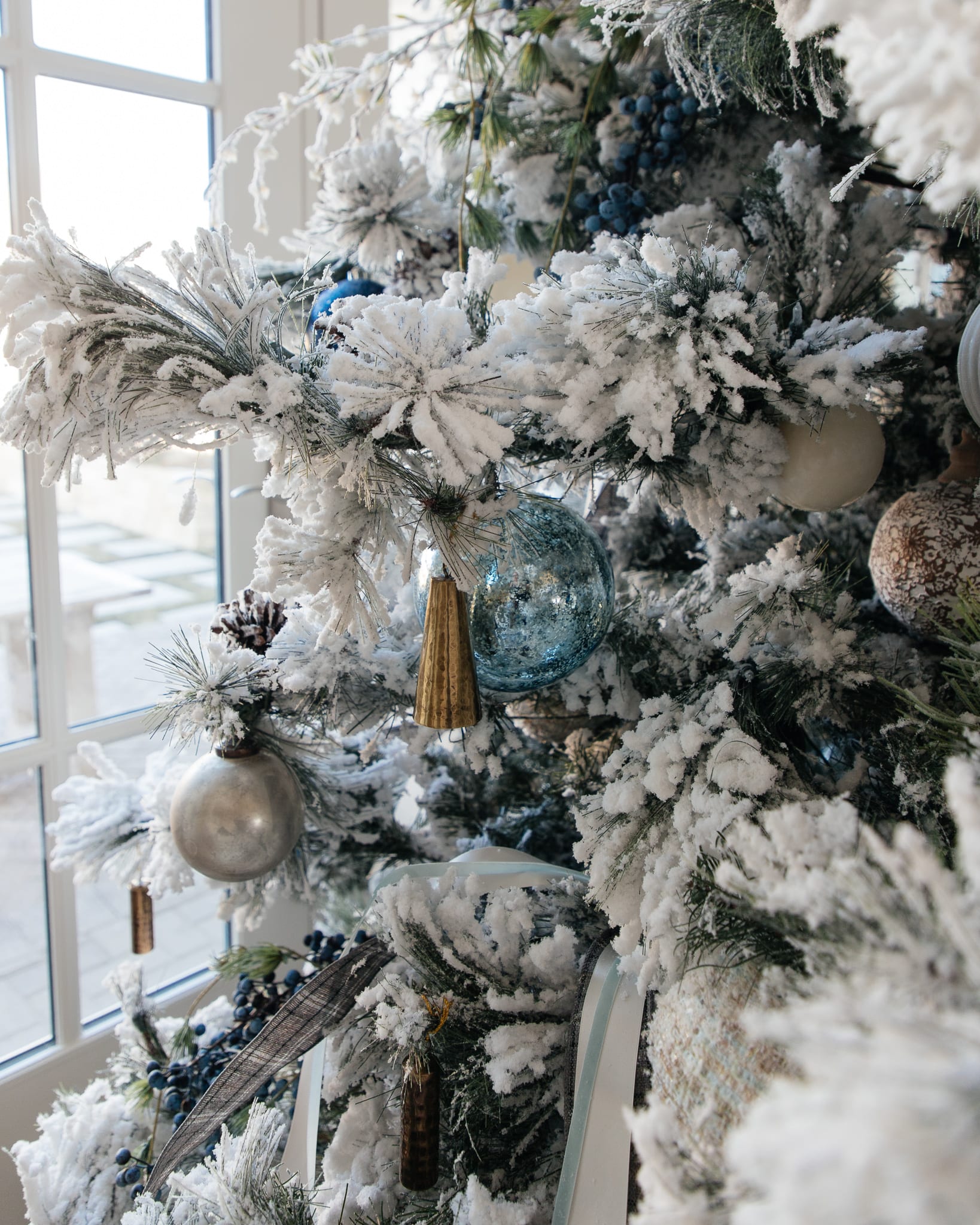 Christmas tree flocked long needle pine christmas tree flocked tree blue decor blue christmas ornaments trimming the tree shades of blue on white blue and cream flocked long needle pine artificial tree blue white ivory cream silver ornaments plaid ribbon