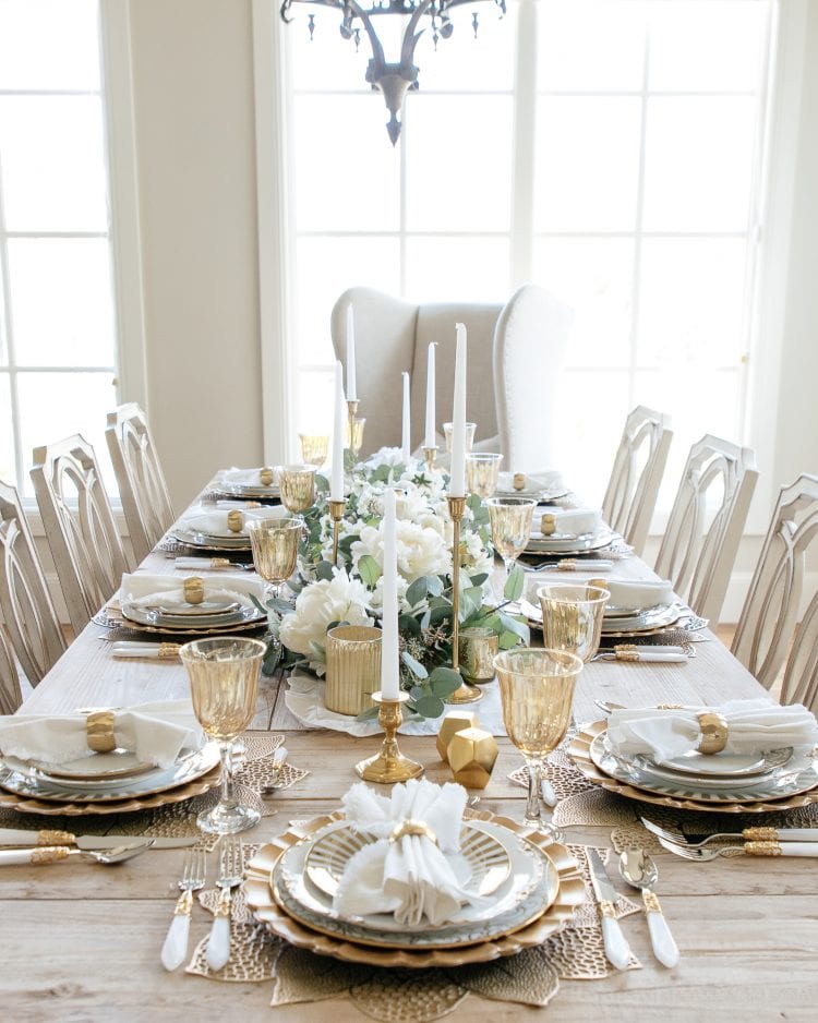Elegant Christmas tableware with white plates and gold cutlery.