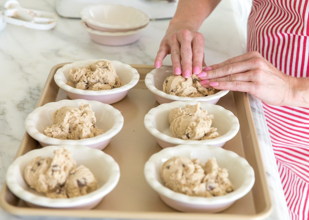 adding chocolate chip cookie dough to mini pie dishes to make a cazookie