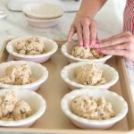 adding chocolate chip cookie dough to mini pie dishes to make a cazookie