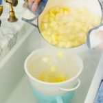 draining water from pot with potatoes