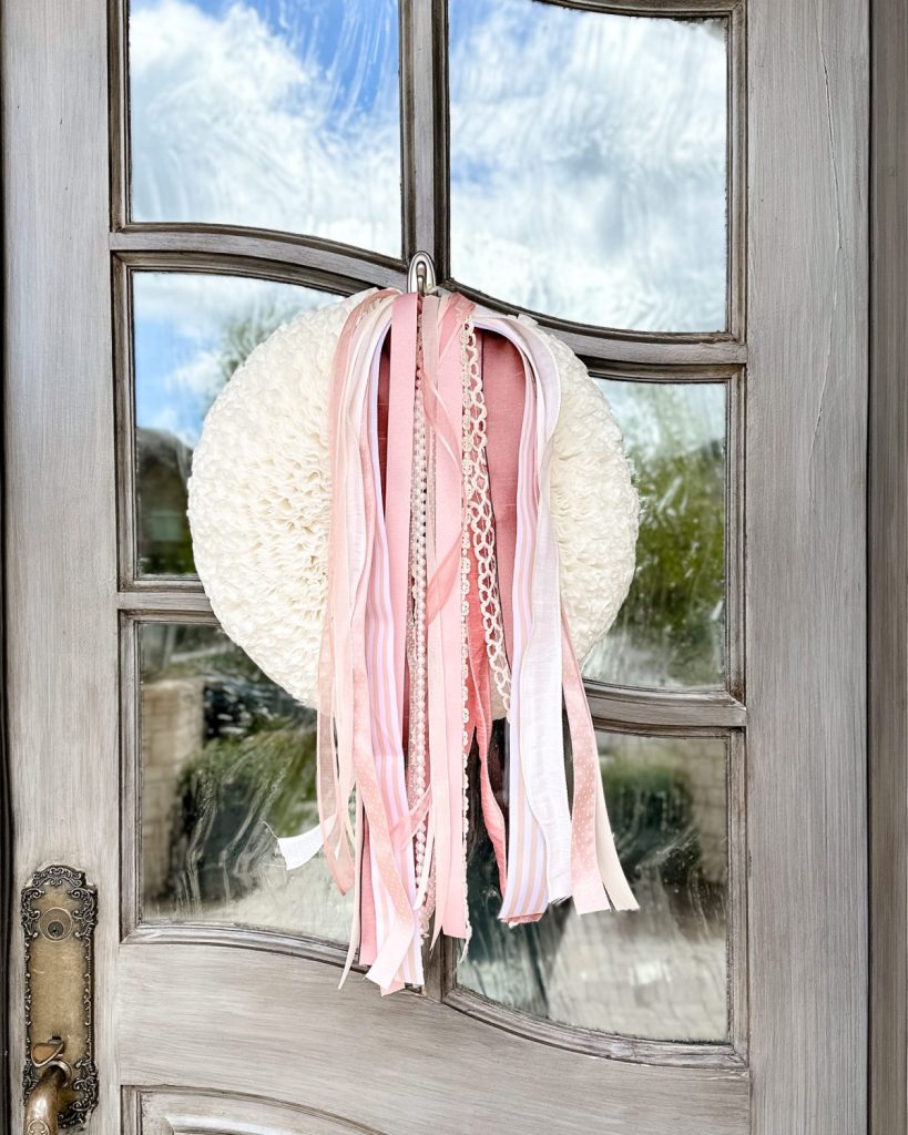 spring coffee filter wreath with dusty pink ribbon bundle on a front door.
