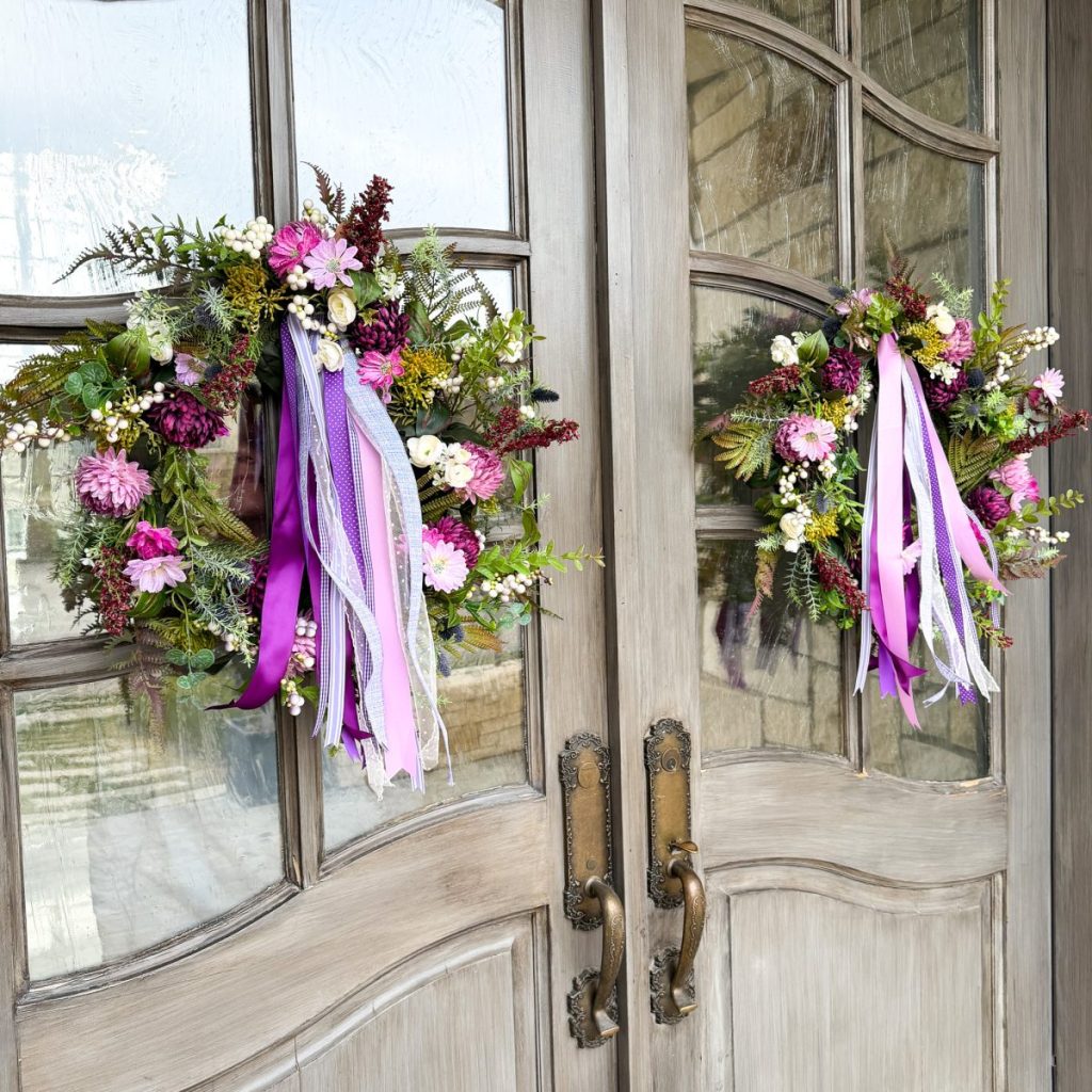 purple spring wreathes on a front door with a purple ribbon bundle attached