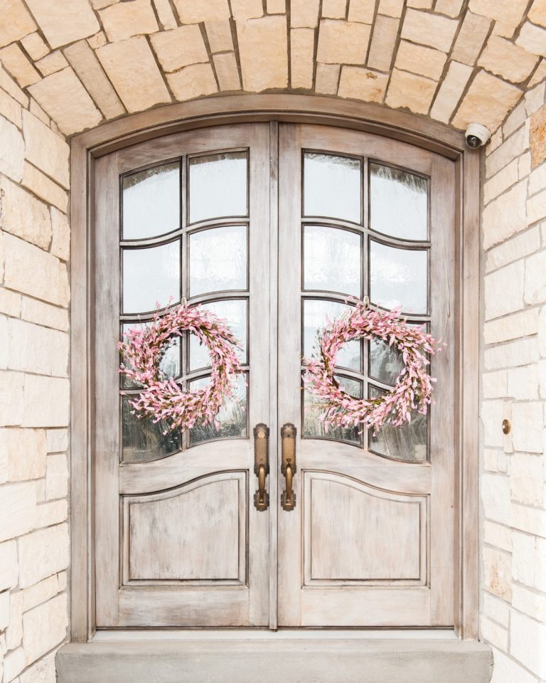 pink cherry blossom wreaths on a gray front door and porch