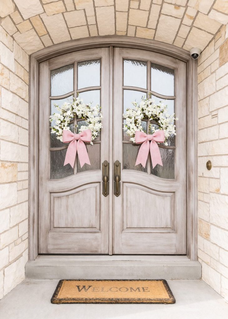 white cherry blossom spring wreath with pink bows on grayish silver doors